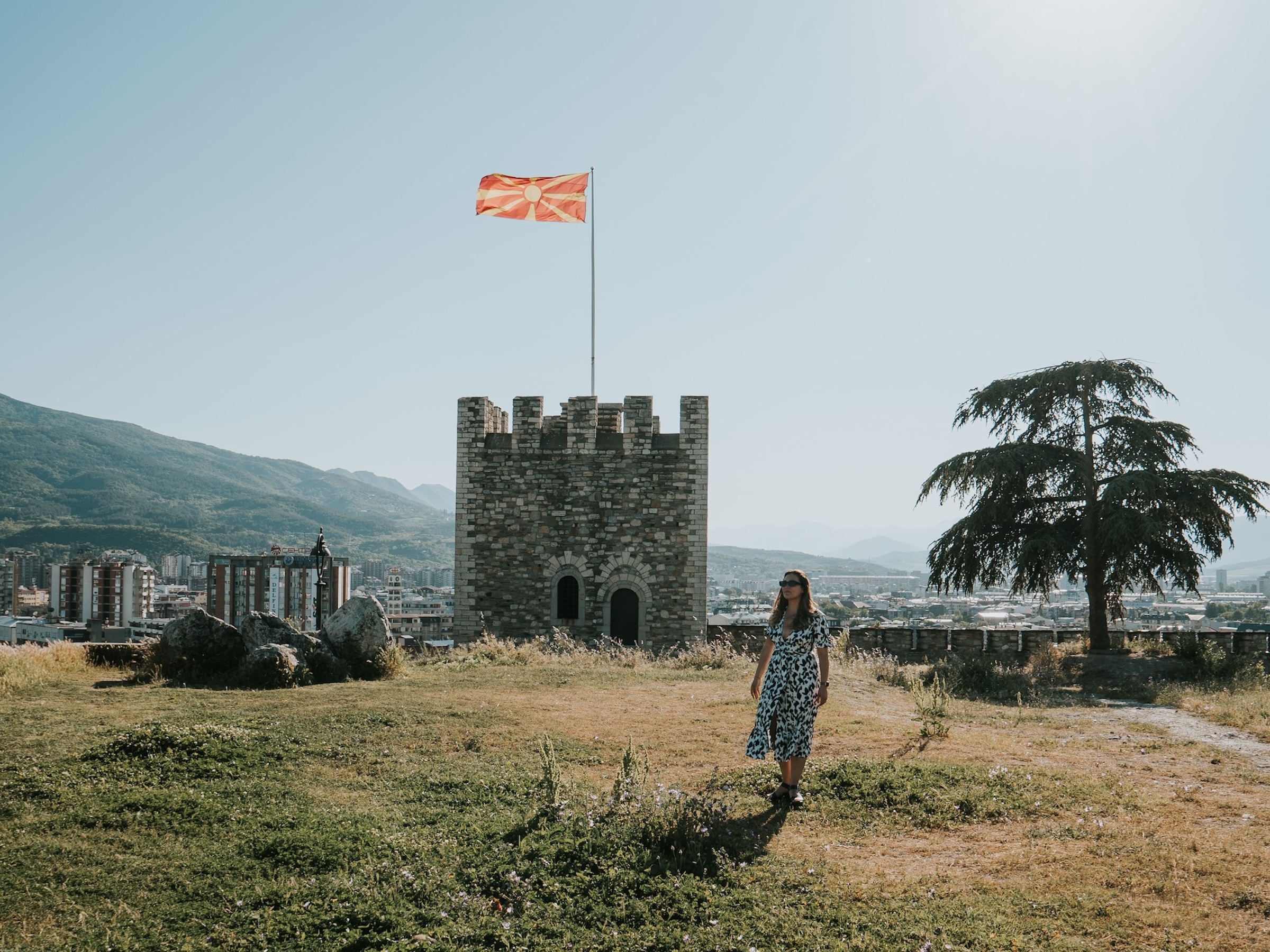 Jazzie in front of Skopje's fort with a North Macedonian flag for Skopje City Guide